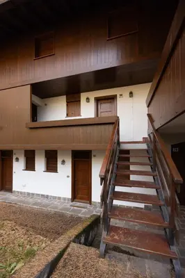 a building with wooden doors and stairs in front at Casa Funivia, immersa nel verde e vicina al centro di Cortina in Cortina dʼAmpezzo