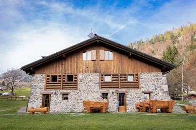 a log building with benches in front of it at Chalet Al Maso Val Calamento in Telve