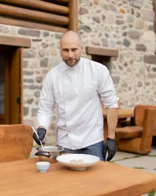 a man is preparing food on a table at Chalet Al Maso Val Calamento in Telve
