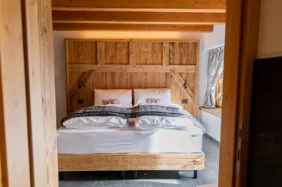 a bedroom with a bed with a wooden headboard at Chalet Al Maso Val Calamento in Telve