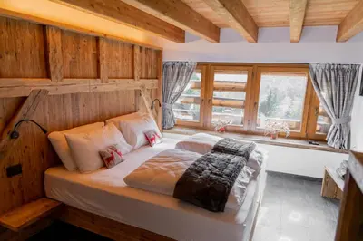 a bedroom with a large bed with wooden walls at Chalet Al Maso Val Calamento in Telve