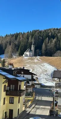 a group of buildings with a windmill in the background at Appartamento Dolomiti Dream 1 in Falcade
