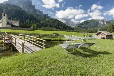 a table and chairs on a field with a bridge at Speckstube Eggerhof in Braies