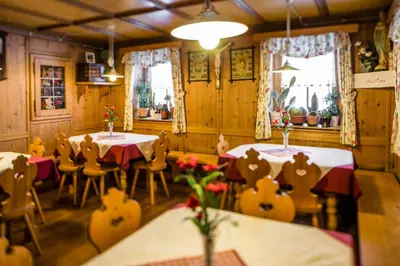 a restaurant with two tables and chairs and windows at Speckstube Eggerhof in Braies