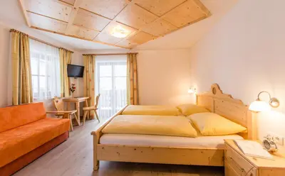 a bedroom with a bed and a couch at Speckstube Eggerhof in Braies