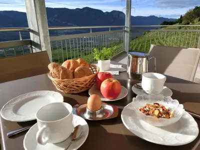 a table with a breakfast of eggs bread and fruit at Fritzenhof in Termeno