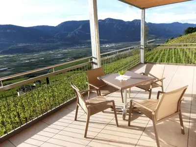 a table and chairs on a balcony with a view at Fritzenhof in Termeno