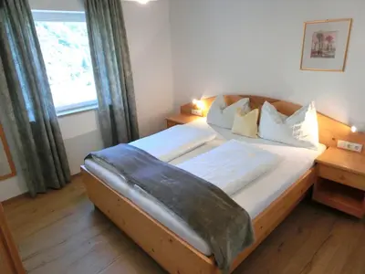 a bedroom with a large bed with a large window at Fritzenhof in Termeno