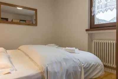a white bed in a room with a mirror at Trilo Ciasa de l'Ora in Cavalese