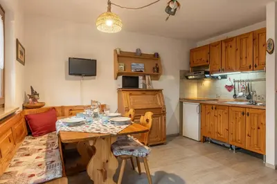 a kitchen with a wooden table and a dining room at Trilo Ciasa de l'Ora in Cavalese