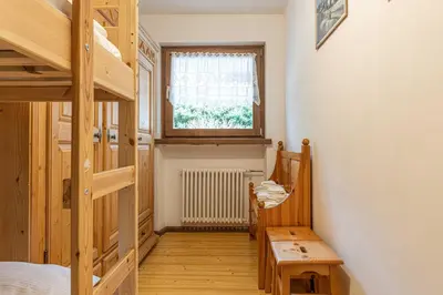 a room with a wooden staircase and a window at Trilo Ciasa de l'Ora in Cavalese