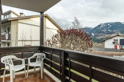 two white chairs sitting on a balcony with mountains at Trilo Ciasa de l'Ora in Cavalese