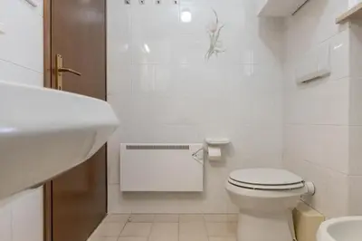a white bathroom with a toilet and a sink at Trilo Ciasa de l'Ora in Cavalese