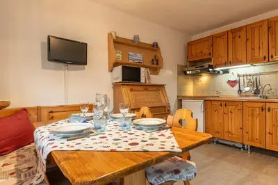 a kitchen with a wooden table with plates and glasses at Trilo Ciasa de l'Ora in Cavalese