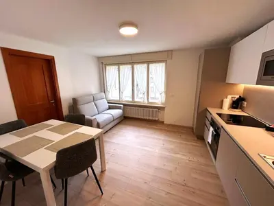 a kitchen and living room with a table and a dining room at Appartamento Dolomiti Dream 2 in Falcade