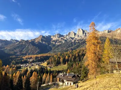 a house on a hill with mountains in the background at Appartamento Dolomiti Dream 2 in Falcade