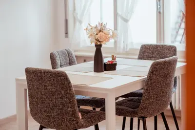 a dining room table with chairs and a vase with flowers at Appartamento Dolomiti Dream 2 in Falcade