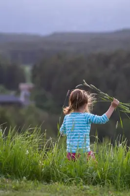 a little girl is playing in the grass at Hof Zerund in Castelrotto