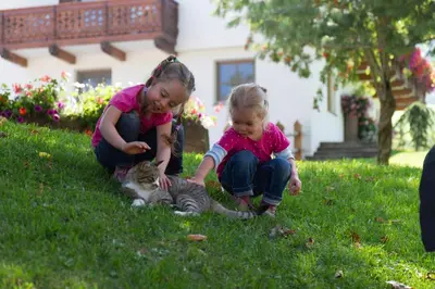 two little girls playing with a kitten in the grass at Hof Zerund in Castelrotto
