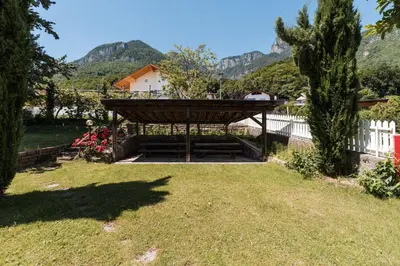 a garden with a pergola with mountains in the background at Apartments Ansitz Wieshof in Castelvecchio