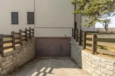 a wooden garage door in a brick retaining wall at Private Veranda - Tiroler Chalet - Near Ski Slopes & Dolomites in Carano