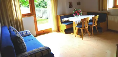 a living room with a table and a blue couch at Tommele Hof in Volser Aicha