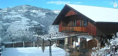 a house covered in snow with a mountain in the background at Tommele Hof in Volser Aicha