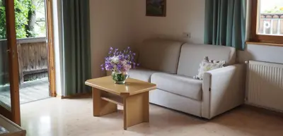 a living room with a couch and a table with flowers on it at Tommele Hof in Volser Aicha