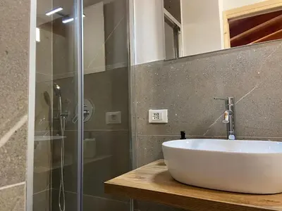 a bathroom with a white sink and a shower at Eco Chalet Nonno Silvano in Bedollo