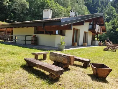 a house with benches in the grass in front of it at Eco Chalet Nonno Silvano in Bedollo