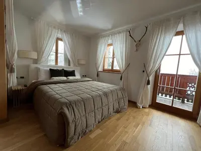a bedroom with a large bed and two windows at Lüch dl Mone y Chalets in Badia