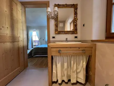 a bathroom with a sink and a mirror and a bed at Lüch dl Mone y Chalets in Badia