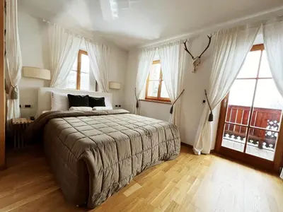 a bedroom with a large bed and two windows at Lüch dl Mone y Chalets in Badia