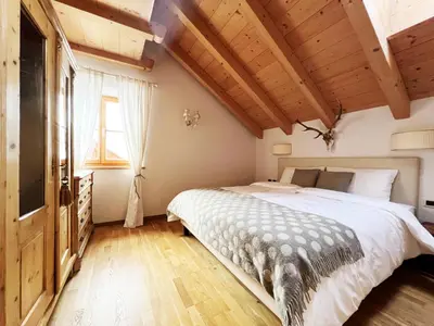 a bedroom with a large bed and a wooden ceiling at Lüch dl Mone y Chalets in Badia