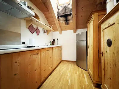 a kitchen with wooden cabinets and a refrigerator at Lüch dl Mone y Chalets in Badia
