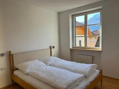 a bedroom with a bed with white blankets and a window at Saint Martin Guest House in Cornaiano