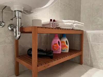 a shelf in a bathroom with bottles of soap and a sink at Saint Martin Guest House in Cornaiano