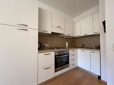a white kitchen with white cabinets and appliances at Saint Martin Guest House in Cornaiano
