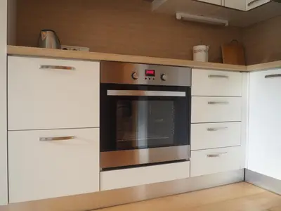 a kitchen with white cabinets and an oven at Saint Martin Guest House in Cornaiano
