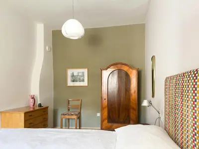 a bedroom with a bed with a wooden door and a chair at apartment beletage in San Lorenzo di Sebato