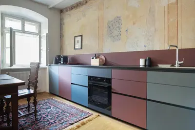 a kitchen with pink and purple cabinets and a table at apartment beletage in San Lorenzo di Sebato