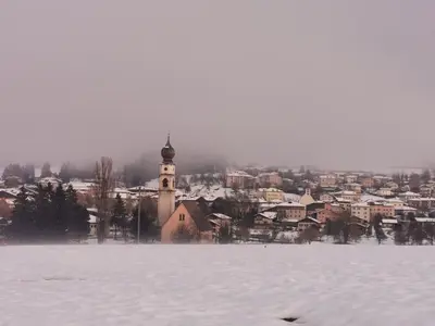 a snow covered town with a clock tower in the distance at Casa della Lavanda in Sarnonico
