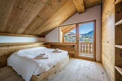 a bedroom with a bed and a large window at Chalet Ronco - Dolomiti Skyline in Cortina dʼAmpezzo