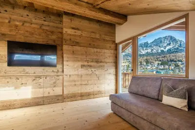 a living room with a couch and a large window at Chalet Ronco - Dolomiti Skyline in Cortina dʼAmpezzo