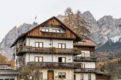 a house with a balcony in front of a mountain at Chalet Ronco - Dolomiti Skyline in Cortina dʼAmpezzo