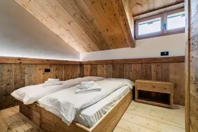 a bed in a wooden room with a window at Chalet Ronco - Dolomiti Skyline in Cortina dʼAmpezzo