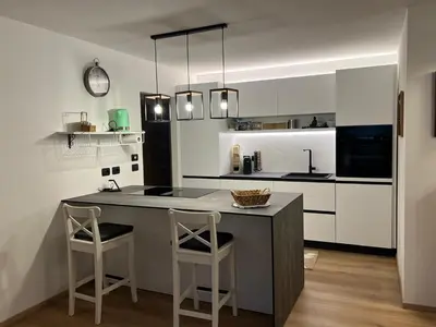 a kitchen with a counter and two stools in it at Casa Carlotta Tesero-Relax and view in Tesero