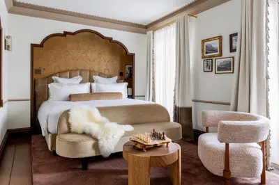 a bedroom with a bed and a chair and a table at Ancora Cortina - The Leading Hotels of the World in Cortina dʼAmpezzo