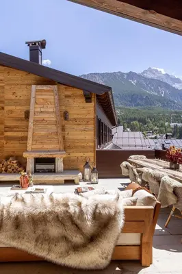 a patio with couches and tables and a building at Ancora Cortina - The Leading Hotels of the World in Cortina dʼAmpezzo