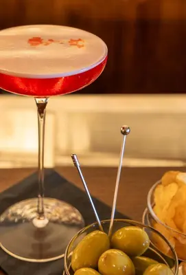 a martini glass and a bowl of grapes on a table at Ancora Cortina - The Leading Hotels of the World in Cortina dʼAmpezzo